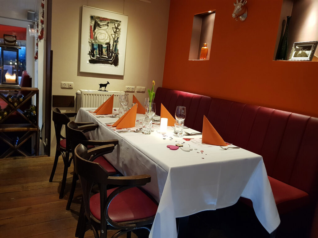 Gastraum mit gedeckter Tafel und roter Sitzbank im Café Zikke